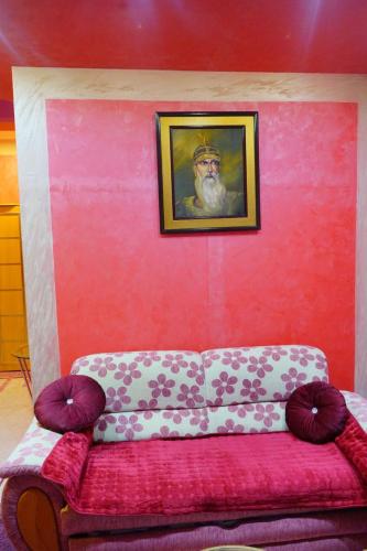 a couch in a room with a painting on a red wall at Apartmani Lazić in Gracanica