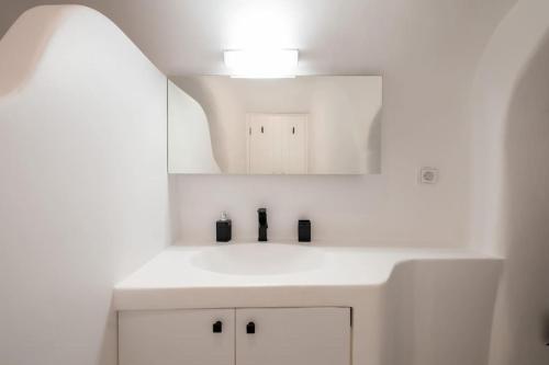 a white bathroom with a sink and a mirror at Akrotiri Hidden Gem in Akrotiri
