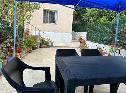 a black table and chairs under a blue umbrella at ML Apartment Saranda in Sarandë