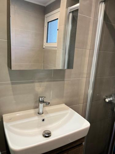 a bathroom with a white sink and a mirror at Cosy new apartment in Néa Michanióna