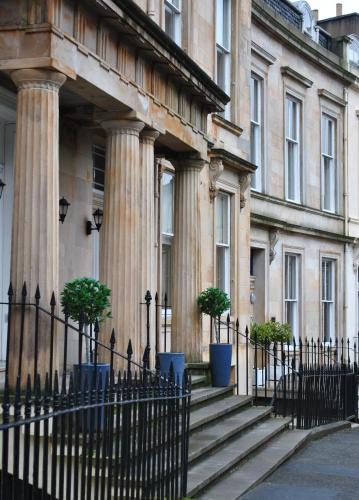 a building with a fence and potted plants in front of it at Dreamhouse Apartments Glasgow West End in Glasgow