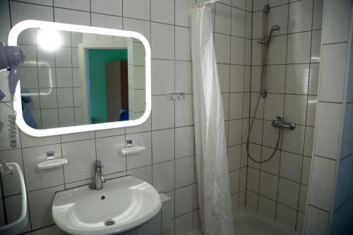 a bathroom with a sink and a shower with a mirror at Garni Hotel Rödelheimer Hof in Frankfurt/Main