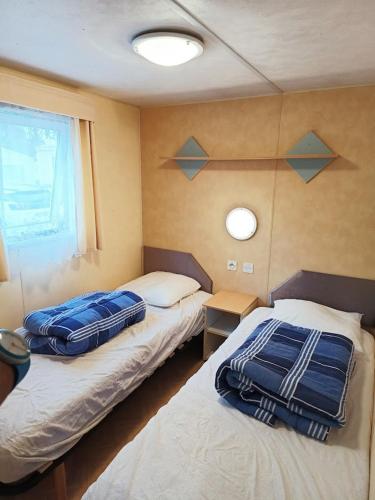 deux lits dans une chambre avec deux fenêtres dans l'établissement Mobilhome Oléron simple et spacieux à 1min de l'Océan, à La Cotinière