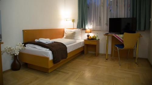 a bedroom with a bed and a desk with a television at Garni Hotel Rödelheimer Hof in Frankfurt/Main