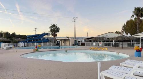 une grande piscine avec des chaises et un toboggan dans l'établissement CAMPING Siblu Le Montourey - LE FARNIENTE, à Fréjus