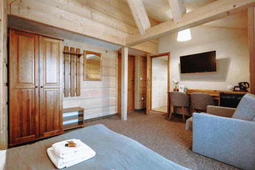 a room with a bed and a desk and a television at Góralski Gościniec & SPA in Poronin