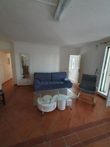 a living room with a blue couch and a glass table at Vila Vistazul in Pataias