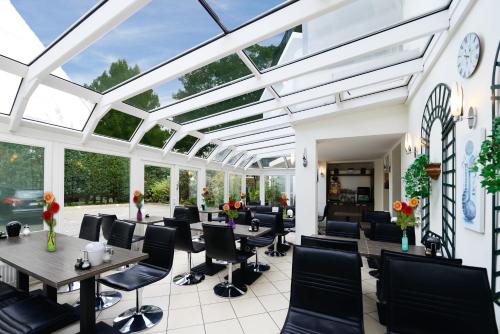 a conservatory with tables and chairs and windows at Hotel Marienthal Garni in Hamburg