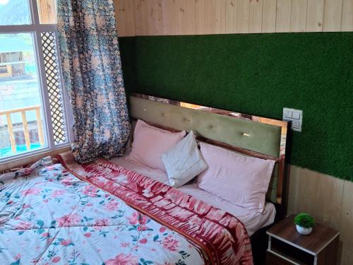 a bedroom with a bed with a green wall and a window at D’SHIEKHS RESORT GUREZ in Kanzalwan