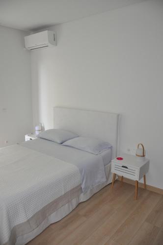 a white bedroom with a bed and a table at Athens Sea Front Apartment - Athenian Riviera in Varkiza