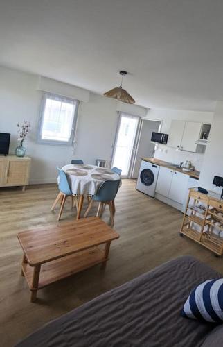 un salon avec une table et des chaises et une cuisine dans l'établissement Les voisins de l'hippodrome, à Pornichet