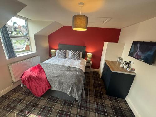 a bedroom with a bed and a red wall at The Prince Albert Pub & Hotel with onsite FREE PARKING 2 minutes from Legoland in Windsor