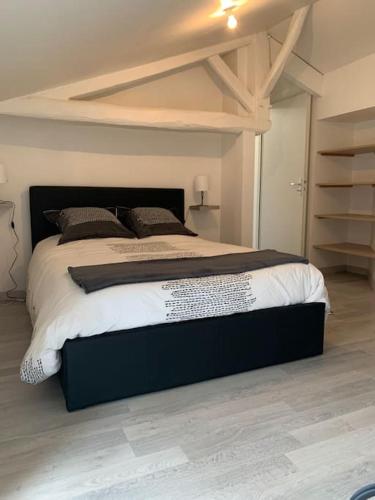 une chambre avec un grand lit dans une pièce dans l'établissement Le Dauphiné, à Mortagne-sur-Sèvre