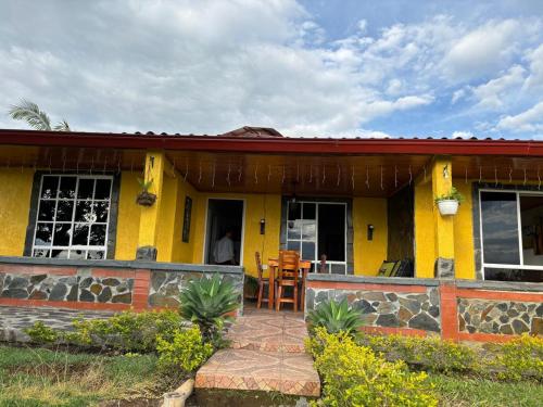 a yellow house with a patio in front of it at Alojamiento EL GITANO in Filandia