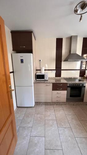 a kitchen with a white refrigerator and a tile floor at CA LIDIA - Apartamentos Turisticos EL BALCONET in Benimantell