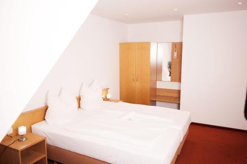 a large white bed in a room with a mirror at Hotel Restaurant Zehntscheune in Sinsheim