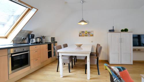a kitchen with a table and chairs in a room at Ferienwohnungen by Weingut Hommes in Ernst Mosel in Ernst