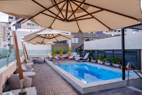 - une piscine avec des parasols dans un bâtiment dans l'établissement Marante Plaza Hotel, à Récife
