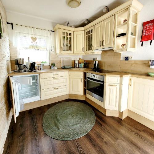 a kitchen with white cabinets and a rug on the floor at Ferienhaus Grüner Bungalow Kontaktloser CheckIn in Stendell