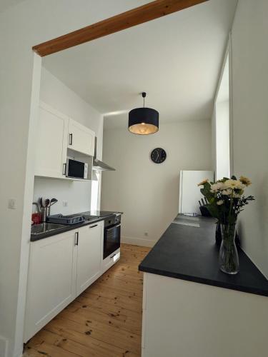 une cuisine avec des armoires blanches et un comptoir noir dans l'établissement La pause roannaise, à Roanne