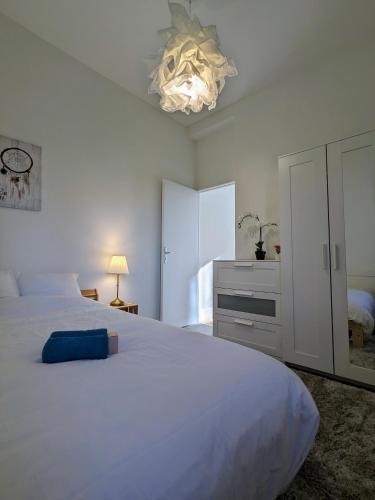 - une chambre avec un grand lit blanc et un lustre dans l'établissement La pause roannaise, à Roanne