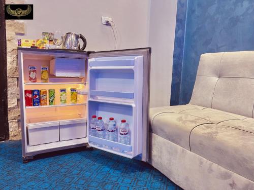 a small refrigerator with its door open next to a couch at Comfort Sphinx Inn in Cairo