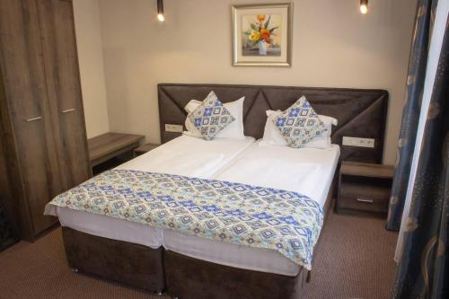 a bedroom with a bed with white sheets and blue pillows at Silk Way in Almaty
