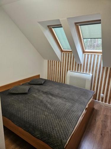 a bedroom with a bed and two windows at Bursztyn 2 in Pobierowo