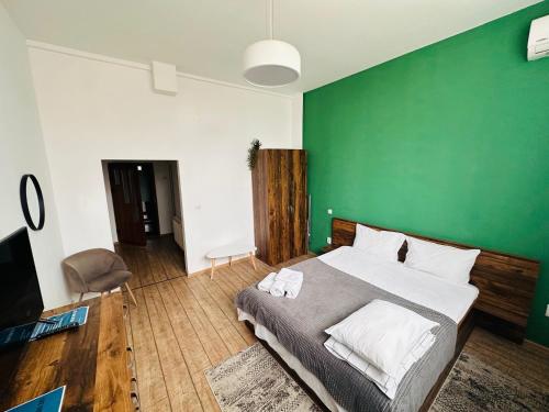 a bedroom with a green wall and a bed at Neva Apartments & Rooms in Făgăraş