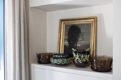 a shelf with a picture and vases on it at Casa TOMA - Luxury Garden House in Arzignano