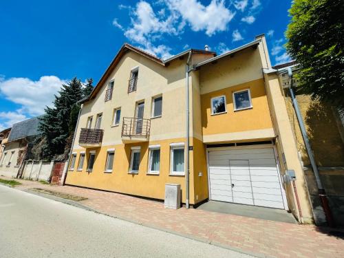 a yellow house with a garage on a street at Gold Apartman in Nagykanizsa