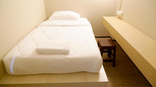 a bed with white sheets and pillows in a room at Shi-ro-i Poshtel in Hat Yai