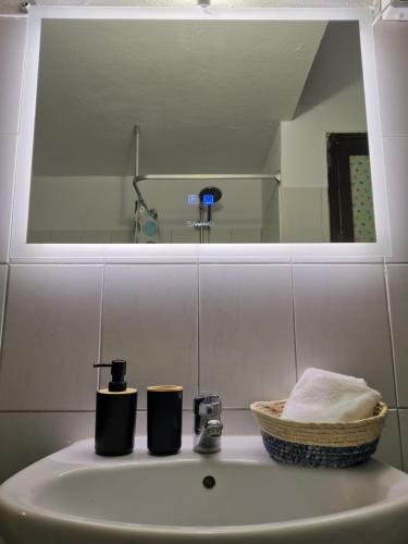a bathroom sink with a mirror and a basket on it at Alana apartment in Ierissos