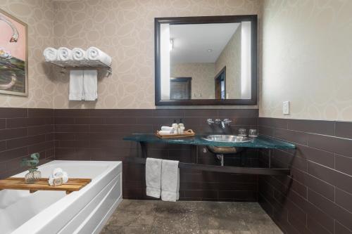 a bathroom with a sink and a tub and a mirror at Oxford Hotel Bend in Bend