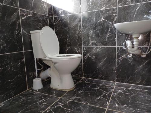 a black tiled bathroom with a toilet and a sink at Ojong's Court Bellville in Cape Town