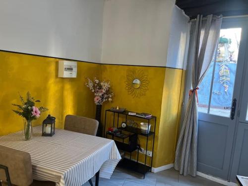 une salle à manger avec une table et un mur jaune dans l'établissement Studio coup de cœur - Lorgues, à Lorgues