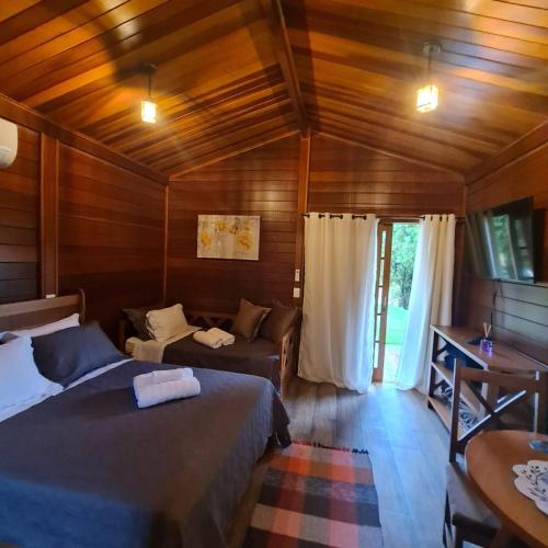 a bedroom with two beds and a couch and a table at Chalé Pavão Recanto Buscapé SFX in São Francisco Xavier