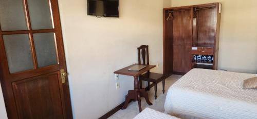 1 dormitorio con cama, escritorio y puerta en Hotel Carmen, en Tarija