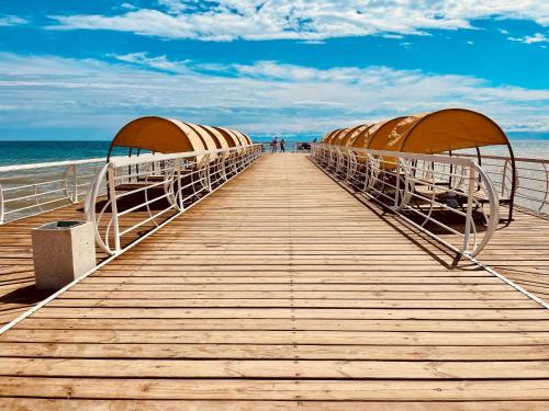 a wooden boardwalk leading to the ocean on a beach at Коттедж в Центре отдыха Palm Beach Иссык-Куль in Chok-Tal