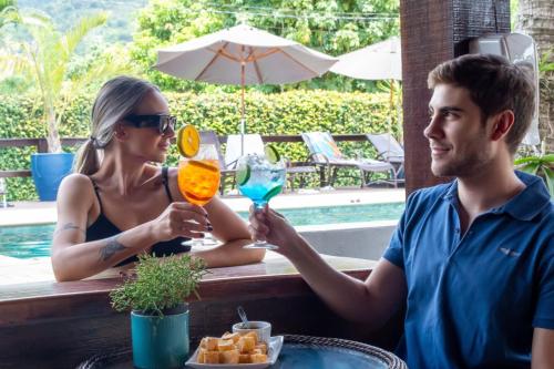 a man and woman sitting at a table with drinks at Vale das Orquídeas Pousada in Socorro