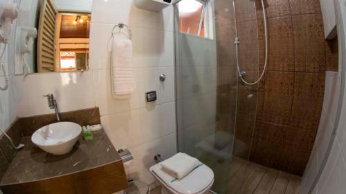 a bathroom with a shower and a toilet and a sink at Vale das Orquídeas Pousada in Socorro