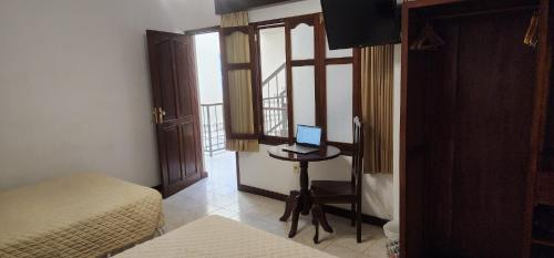 Habitación con 2 camas y escritorio con ordenador portátil. en Hotel Carmen, en Tarija