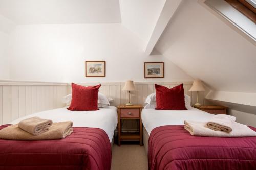 two beds in a attic room with red pillows at The Byre, Heritage Escapes, Field House Farm in Bempton