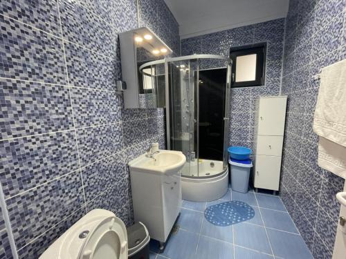a blue tiled bathroom with a toilet and a sink at Apartament Sunshine in Năvodari