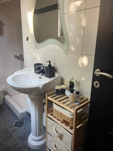 a bathroom with a white sink and a mirror at Medusa Apartment in Artemida