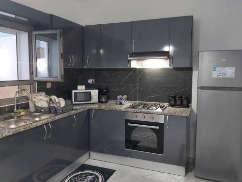 eine Küche mit einem Herd, einer Spüle und einem Kühlschrank in der Unterkunft Villa LELLA HADHERYA in Taguermess