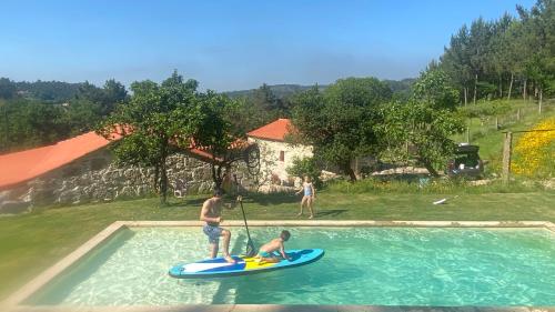 two men on a paddle board in a swimming pool at Casa de Cossourado in Cossourado