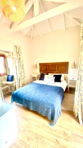 a bedroom with a large bed with a blue blanket at Casa de Cossourado in Cossourado