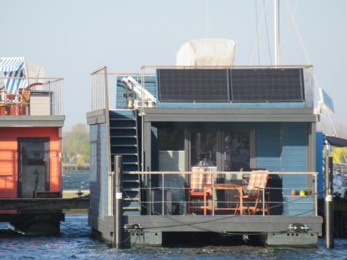 a house on a boat in the water at Hausboot Kaddi`s SunDREAM - Huus & Meer in Fehmarn