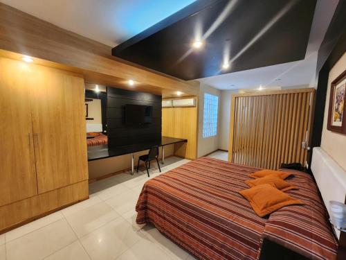 Dormitorio con cama, escritorio y TV en Hotel El Brujo Centro Histórico, en Trujillo